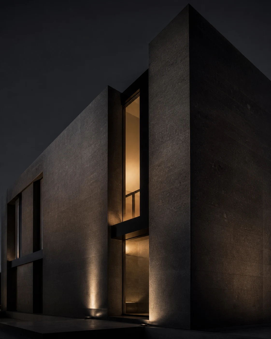 Monolithic black-stone architecture illuminated by warm light at dusk